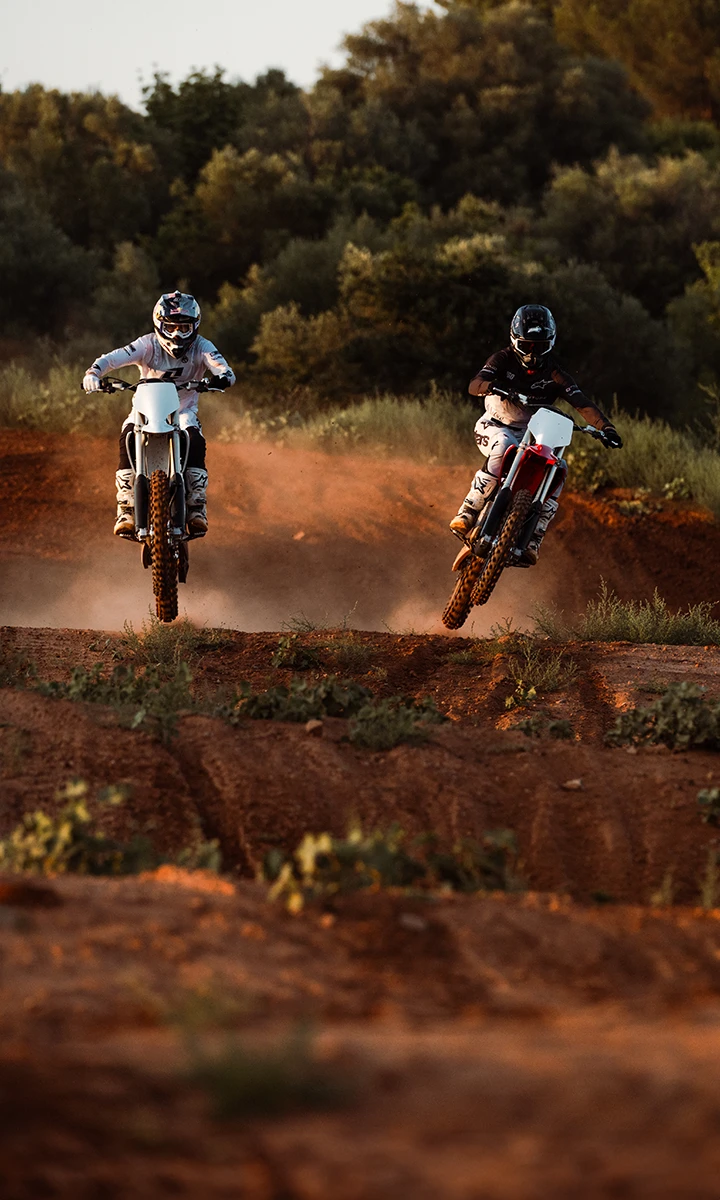 Dwa elektryczne crossy Stark Varg w locie nad hopką na torze motocrossowym
