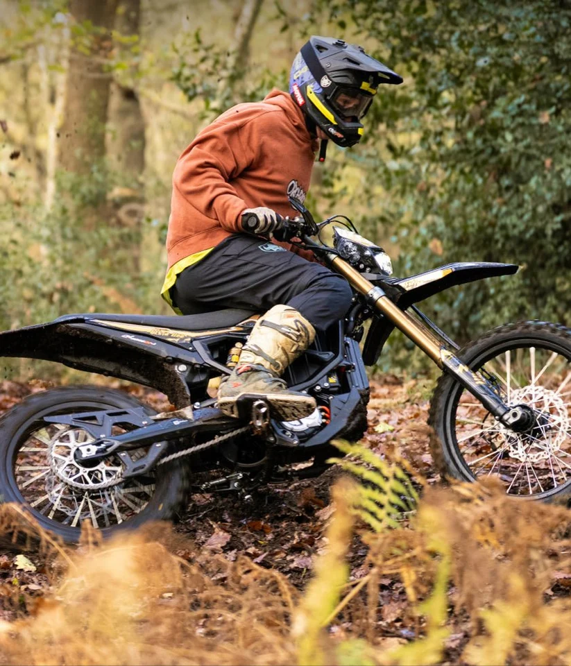 Rider na Sur-Ron Ultra Bee w leśnym terenie między drzewami