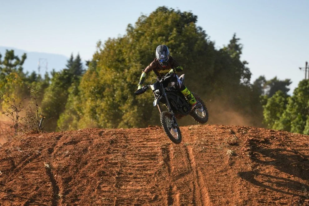 Rider skacze na Sur-Ron Ultra Bee z ziemnej górki na torze
