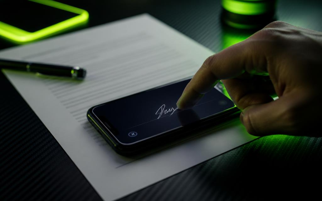 Podpis elektroniczny palcem na ekranie telefonu obok umowy najmu