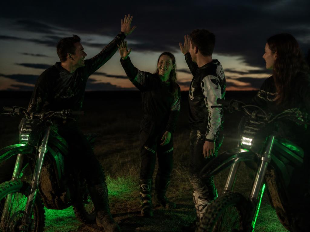 Grupa motocyklistów przy elektrycznych motocyklach o zmierzchu